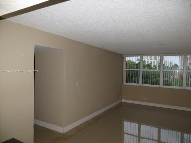 tiled spare room with baseboards and a textured ceiling