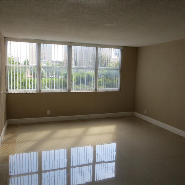 spare room with baseboards, tile patterned floors, and a wealth of natural light