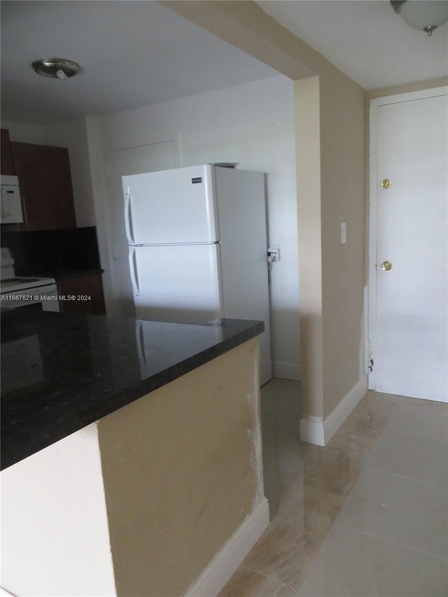 kitchen featuring freestanding refrigerator, dark countertops, and baseboards