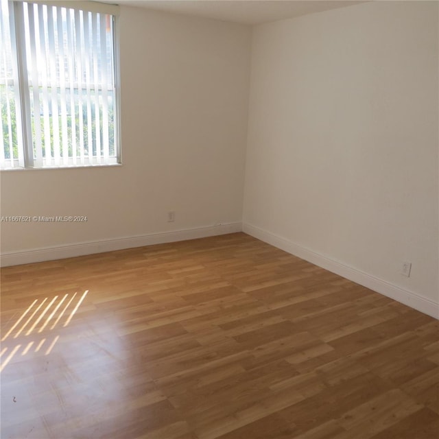 empty room with baseboards and light wood-type flooring