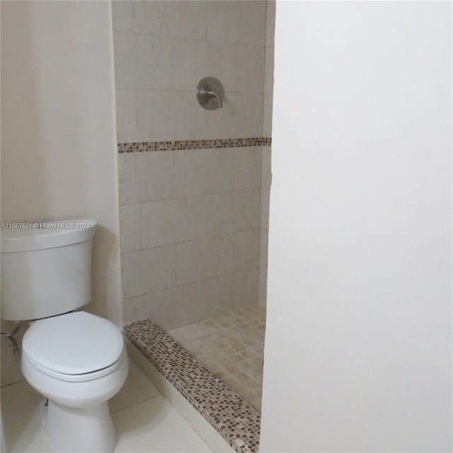 bathroom with tile patterned flooring, tiled shower, and toilet