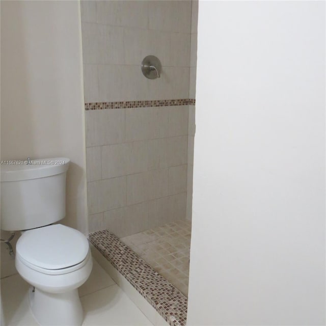bathroom featuring toilet, tile patterned flooring, and a stall shower