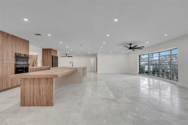 kitchen with an island with sink, black appliances, ceiling fan, and sink