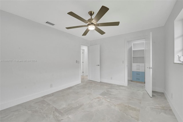 unfurnished bedroom with a spacious closet, a closet, and ceiling fan