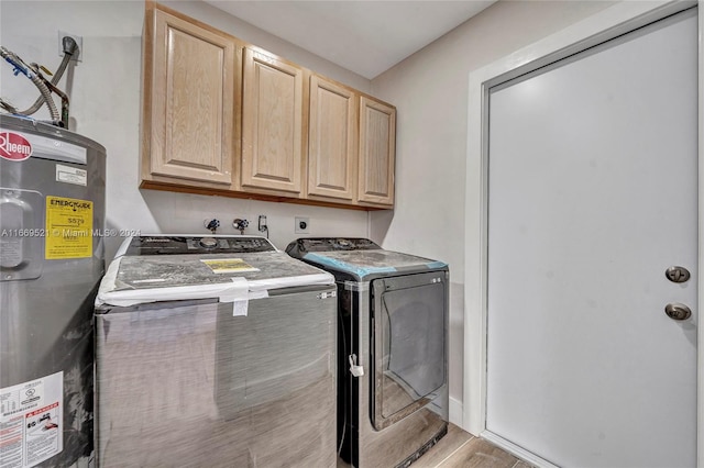 clothes washing area featuring gas water heater, light hardwood / wood-style flooring, washer and dryer, and cabinets