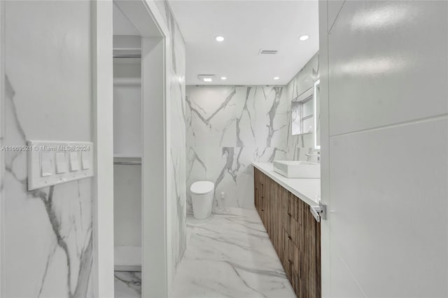 bathroom with vanity, tile walls, and toilet