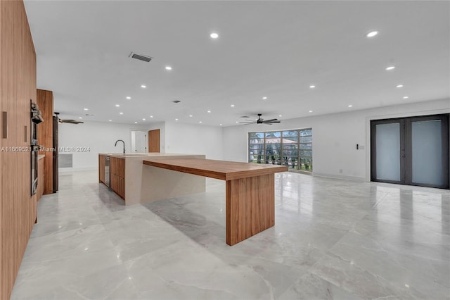 kitchen featuring wood walls, a kitchen island with sink, and sink