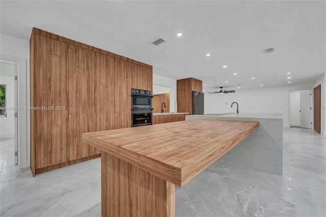 kitchen featuring kitchen peninsula, black double oven, ceiling fan, and sink