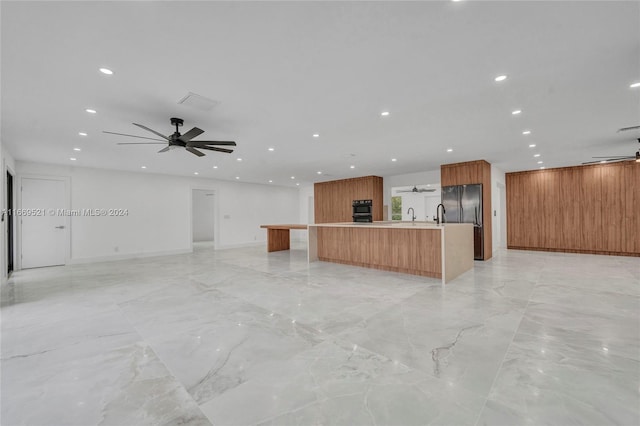 kitchen featuring black appliances, ceiling fan, and a spacious island