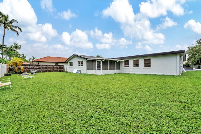 back of property with a sunroom and a lawn