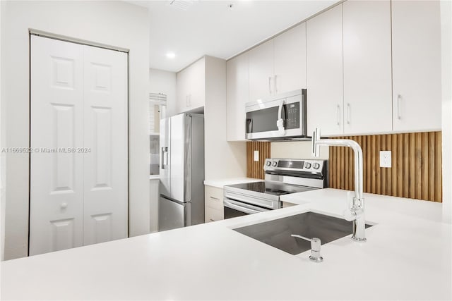 kitchen with appliances with stainless steel finishes, white cabinetry, and sink