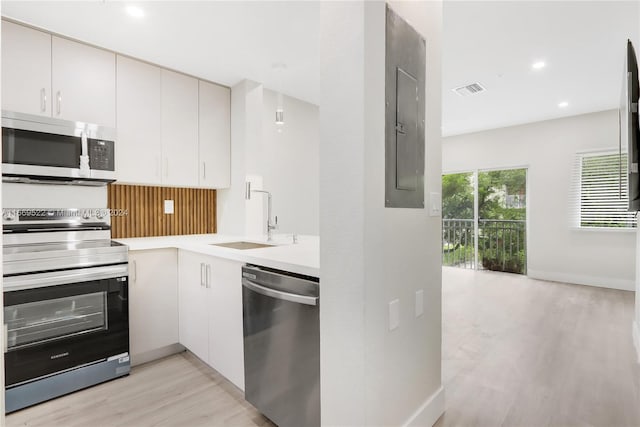 kitchen featuring sink, white cabinetry, stainless steel appliances, and light hardwood / wood-style flooring