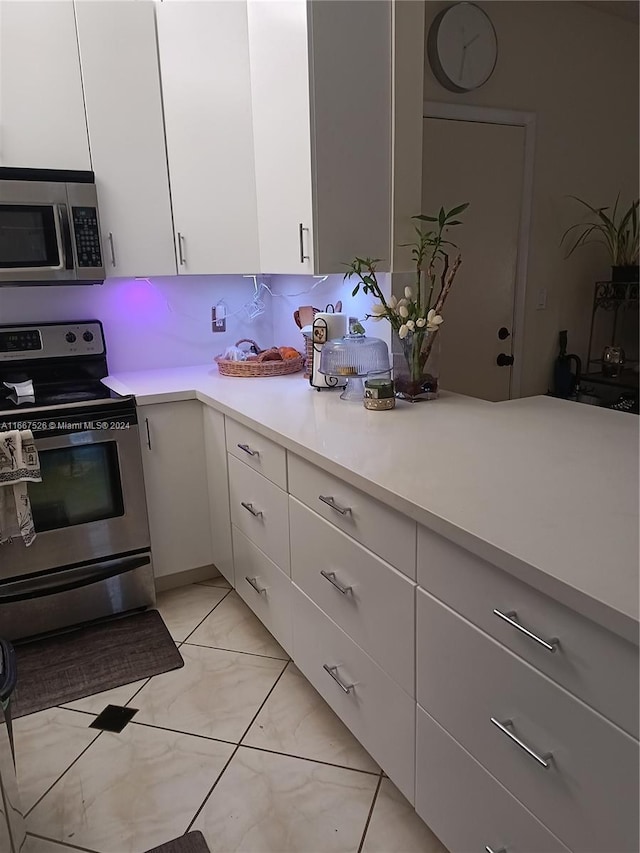 kitchen with white cabinets, appliances with stainless steel finishes, and backsplash