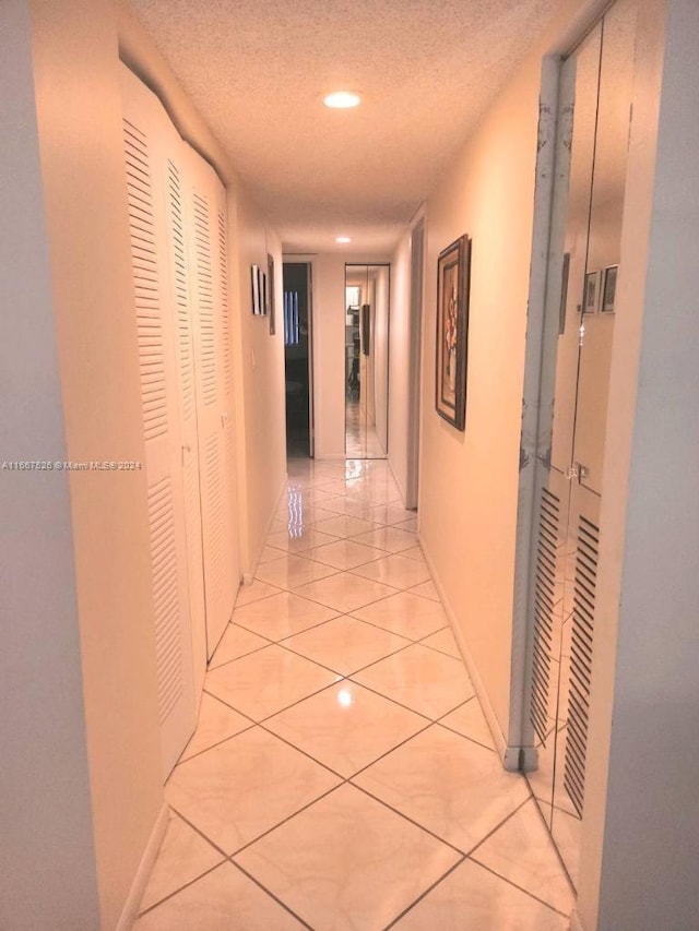 hall featuring a textured ceiling and light tile patterned flooring