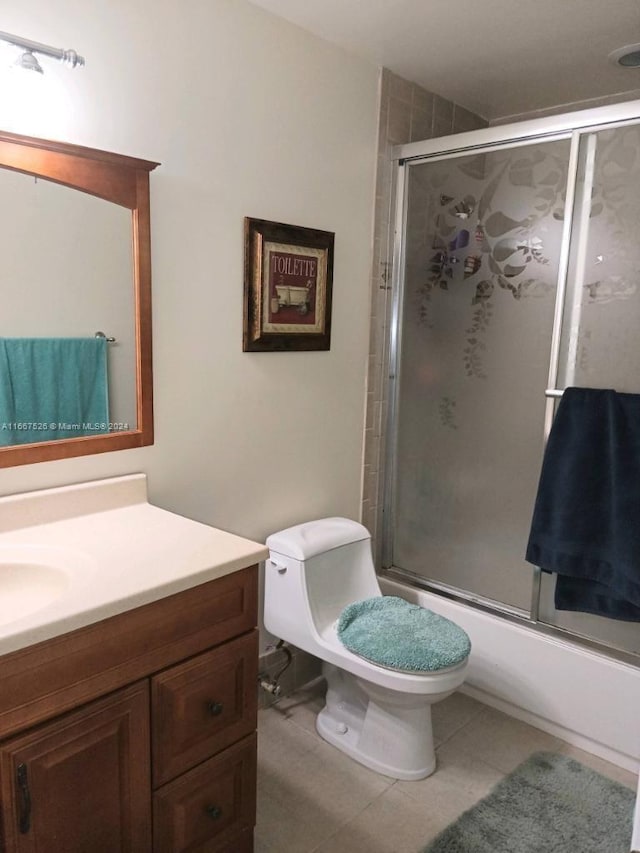 full bathroom with combined bath / shower with glass door, tile patterned floors, vanity, and toilet