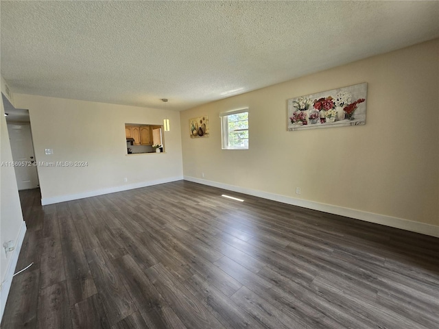 spare room featuring a textured ceiling and dark hardwood / wood-style flooring