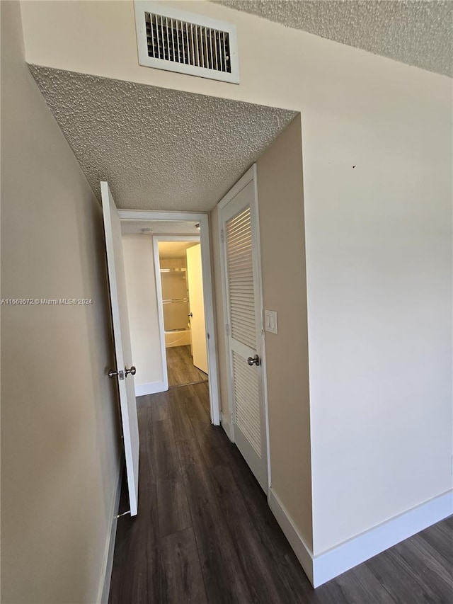 hall featuring a textured ceiling and dark wood-type flooring