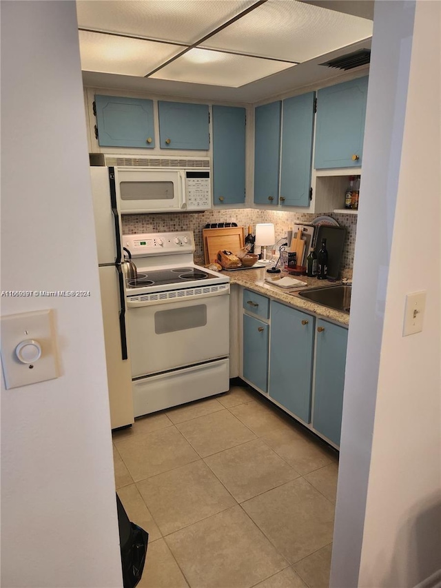 kitchen featuring decorative backsplash, white appliances, light tile patterned floors, and blue cabinetry