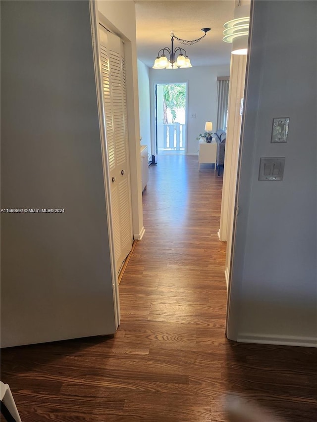 hall featuring dark hardwood / wood-style floors and a notable chandelier