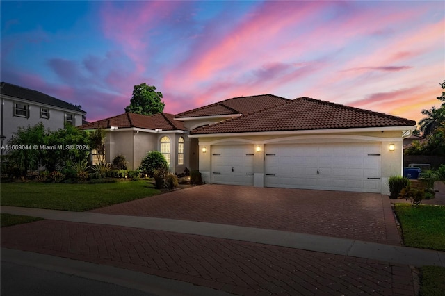 mediterranean / spanish home with a garage and a lawn