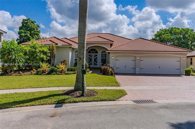 mediterranean / spanish-style house with a garage and a front lawn