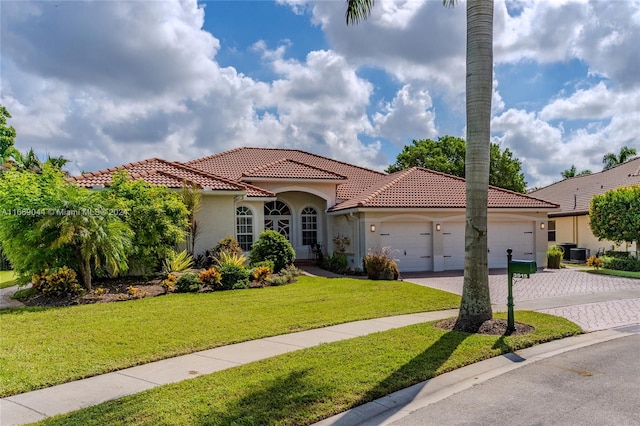 mediterranean / spanish house featuring central AC unit, a front yard, and a garage