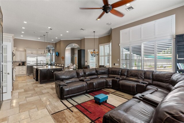 living room featuring ornamental molding, ceiling fan with notable chandelier, and sink