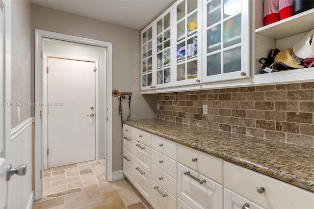 kitchen featuring light stone counters, white cabinetry, and backsplash