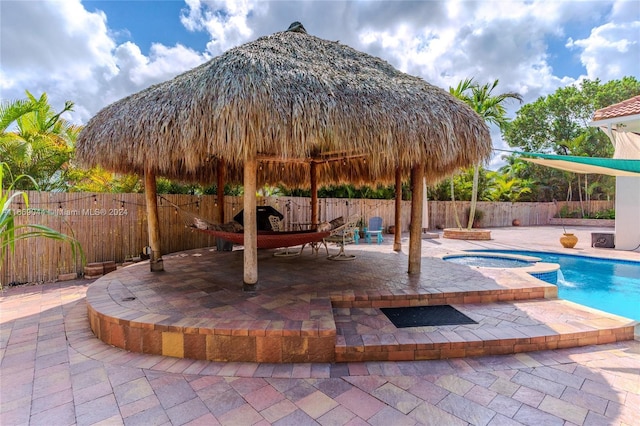 view of patio / terrace with a swimming pool with hot tub and a gazebo