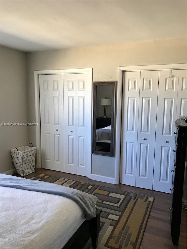 bedroom with multiple closets and dark hardwood / wood-style flooring