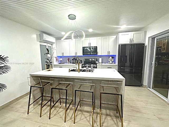 kitchen with white cabinets, a center island with sink, appliances with stainless steel finishes, and a breakfast bar area