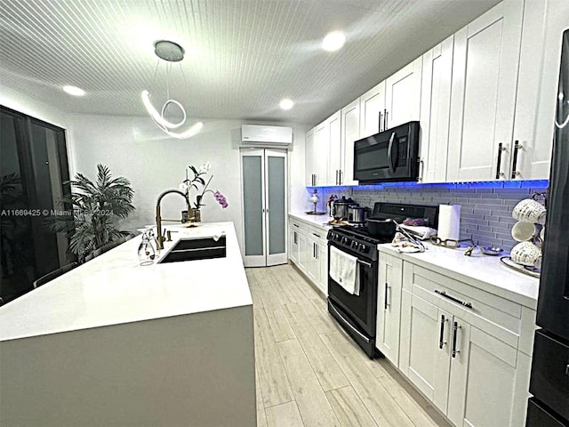 kitchen with white cabinetry, black appliances, light hardwood / wood-style flooring, a kitchen island with sink, and sink