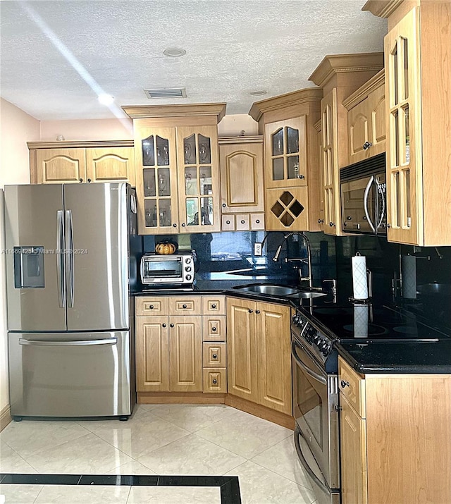 kitchen with decorative backsplash, light tile patterned flooring, stainless steel appliances, a textured ceiling, and sink