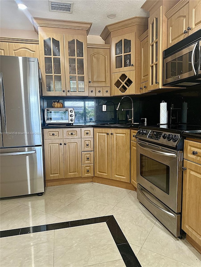 kitchen with appliances with stainless steel finishes, decorative backsplash, light tile patterned floors, a textured ceiling, and sink