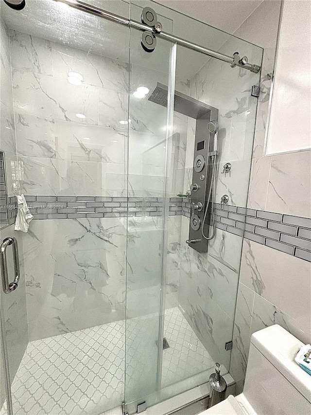 bathroom featuring walk in shower, tile walls, and toilet