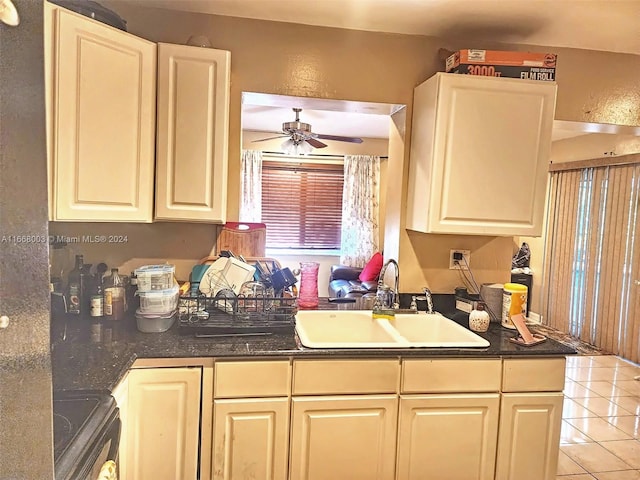 kitchen with light tile patterned floors, stove, sink, and ceiling fan