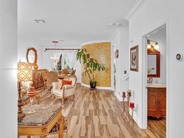 hallway with crown molding, a chandelier, sink, and light wood-type flooring