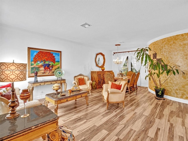 living room with an inviting chandelier, ornamental molding, and light wood-type flooring