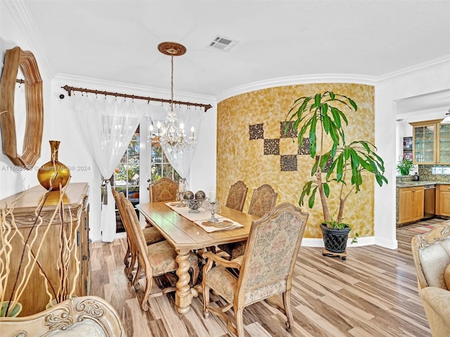 dining space with an inviting chandelier, light hardwood / wood-style flooring, and crown molding