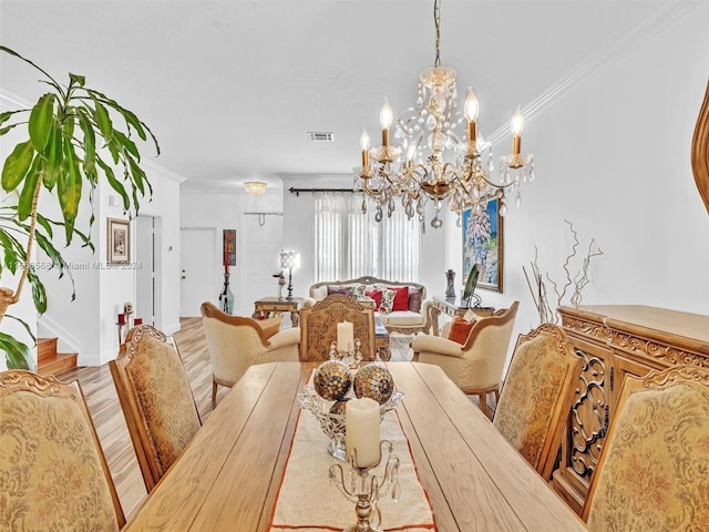 dining area with crown molding, light hardwood / wood-style flooring, and a chandelier