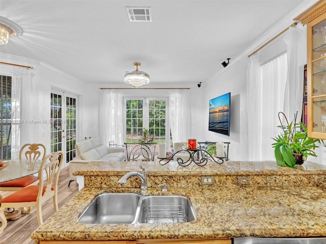 kitchen with french doors, light hardwood / wood-style flooring, sink, light stone countertops, and crown molding