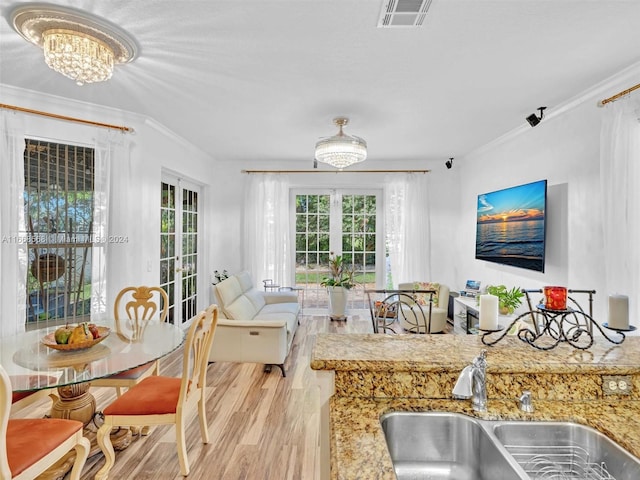 living room with ornamental molding, sink, light hardwood / wood-style flooring, and a notable chandelier