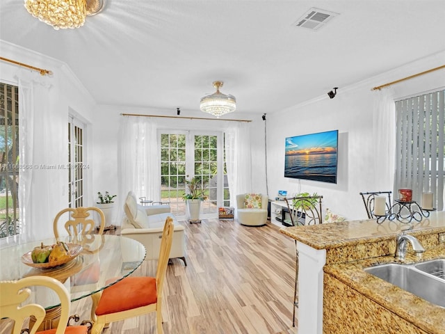 interior space featuring a notable chandelier, ornamental molding, light hardwood / wood-style floors, french doors, and sink