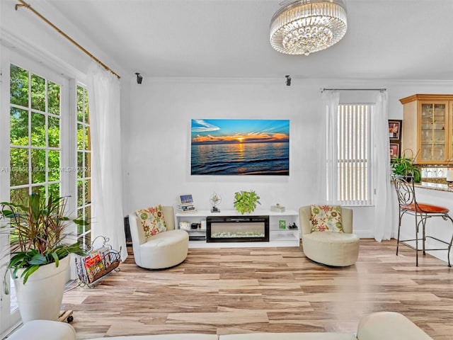 living room featuring ornamental molding, a chandelier, and light hardwood / wood-style floors