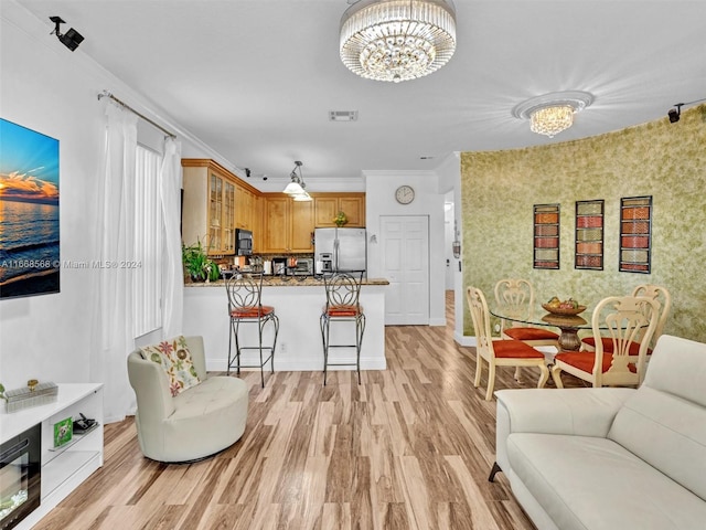 living room with an inviting chandelier, ornamental molding, and light wood-type flooring