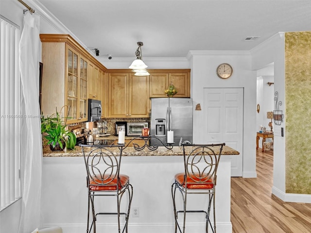 kitchen with stone counters, kitchen peninsula, light hardwood / wood-style floors, stainless steel appliances, and a breakfast bar