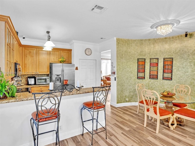 kitchen featuring hanging light fixtures, stainless steel refrigerator with ice dispenser, crown molding, light stone counters, and light hardwood / wood-style floors