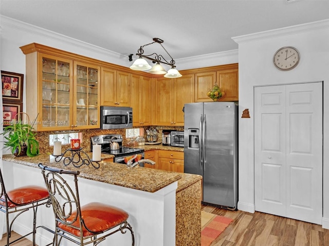 kitchen with appliances with stainless steel finishes, kitchen peninsula, light stone counters, and a kitchen breakfast bar