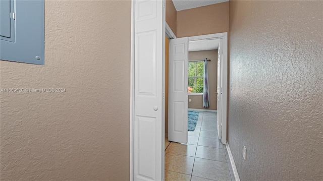 hallway featuring electric panel and light tile patterned floors