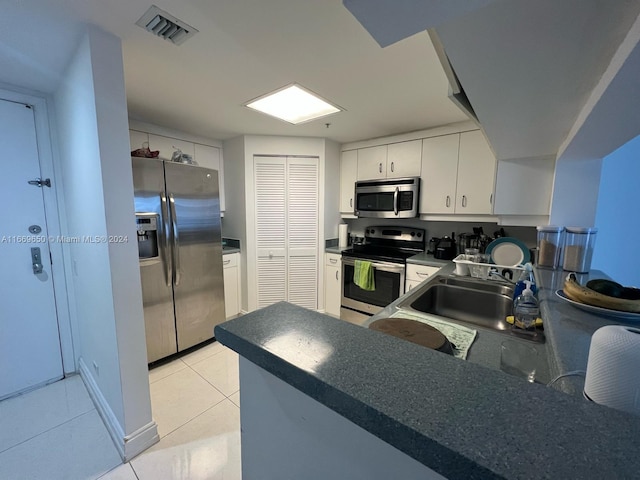 kitchen with light tile patterned flooring, sink, stainless steel appliances, and white cabinets